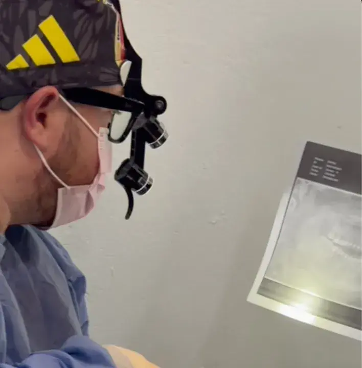 Dr. Juan Durán revisando una radiografía panorámica dental con lupas quirúrgicas